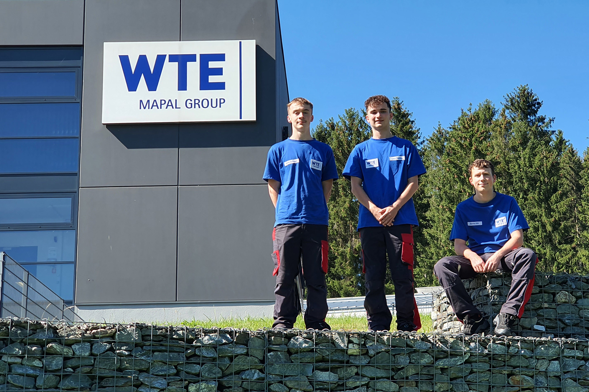 Three new trainees in front of the plant in Ehrenfriedersdorf.